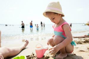 Cute little girl playing with sand on the beach at summer day. photo