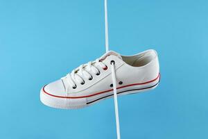 White casual sneakers on blue background, creative minimalism photo