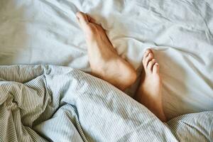 Female legs in the bed under blanket photo