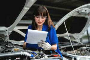 A female mechanic checking vehicle safety in a car service center. Woman mechanic fixing engine. Concept of car repair, engine repair. photo