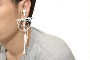 a man with tangled headphones in a twisted mess isolate white background photo