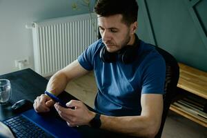 Bored man playing smartphone while working at home office photo