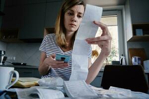 Woman calculating payment bill in kitchen photo