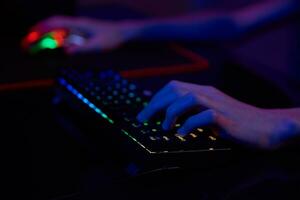 Gamer play computer game, use rgb neon colored keyboard photo