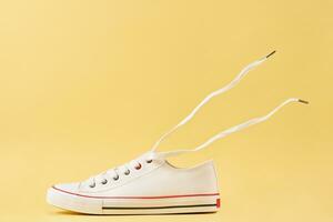 White casual sneakers on yellow background, creative minimalism photo