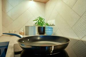 Frying pan on induction hob at kitchen photo