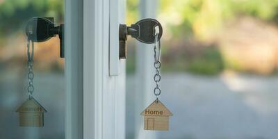 la llave del propietario para desbloquear la casa está enchufada en la puerta. casa de segunda mano en alquiler y venta. llavero está soplando en el viento. hipoteca para casa nueva, compra, venta, renovación, inversión, propietario, patrimonio foto