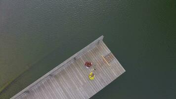 zwei Menschen sind Sitzung auf ein hölzern Seebrücke im das Wasser video