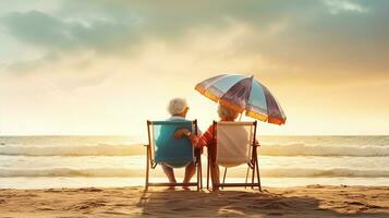 Senior couple sitting on the beach at sunset photo