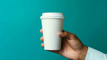 Male hand holding a paper cup of coffee on the blue background. photo