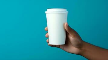 Male hand holding a paper cup of coffee on the blue background. photo
