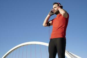 A closeup shot of a young male in red headphone listening to music while working out in the street photo