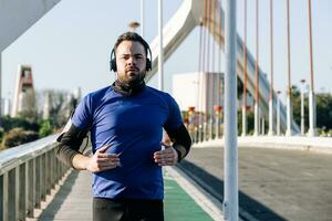 joven hombre corriendo y escuchando a música en un urbano zona foto