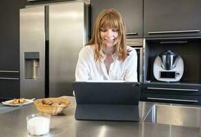 joven ruso mujer mirando a ordenador portátil computadora en un cocina foto