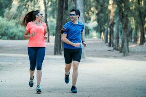 Pareja corriendo en un parque mirando a cada otro y sonriente como ellos escucha a música foto