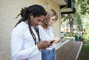 negro chico y caucásico niña acecho y chateando con el célula teléfono. foto