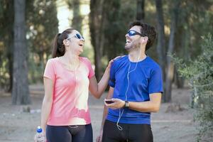 imagen de emocionado hombre y mujer con auriculares escuchando a música en célula Los telefonos en el parque foto