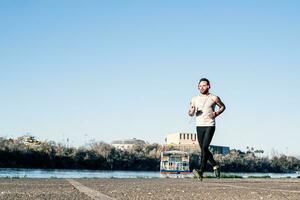 young man running around the harbor and listening to music with a pair of headphones photo