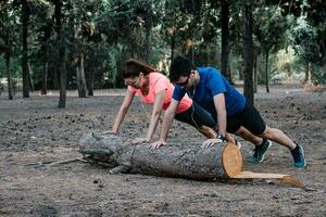 couple doing push-ups on a log in a park photo