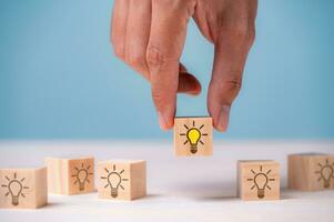 Leader choosing the best new idea with light bulb icon on wooden blocks. Explore creative design, solutions, strategy reviews. Inspiring innovation and teamwork. photo