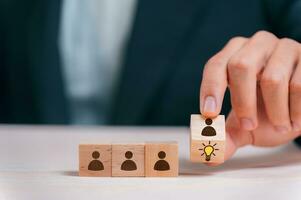 Leader choosing the best new idea with light bulb icon on wooden blocks. Explore creative design, solutions, strategy reviews. Inspiring innovation and teamwork. photo