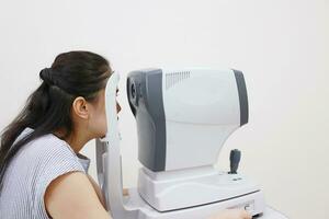 Eye exam concept, woman eye test in clinic, beautiful girl wearing eyeglass on blur optical shop background photo