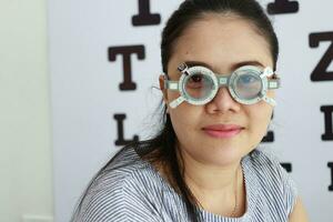 Eye exam concept, woman eye test in clinic, beautiful girl wearing eyeglass on blur optical shop background photo