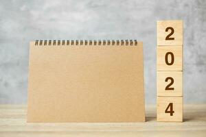 2024 Happy New Year with blank notebook and wooden number. countdown, Resolution, Goals, Plan, Action and Mission Concept photo