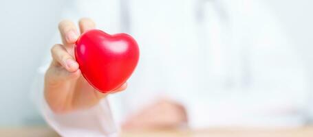 Doctor hand holding red heart shape in hospital. love, donor, world heart day, world health day, CSR donation and Insurance concepts photo