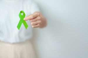 Woman holding green Ribbon for world Lymphoma Awareness September month, world Mental Health Day, Liver, Gallbladders, bile duct, cervical, kidney Cancer. Healthcare and world cancer day concept photo