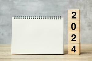2024 Happy New Year with blank notebook and wooden number. countdown, Resolution, Goals, Plan, Action and Mission Concept photo