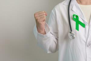 Doctor with green Ribbon for world Mental Health Day, Liver, Gallbladders, bile duct, cervical, kidney Cancer and Lymphoma Awareness month. Healthcare and world cancer day concept photo