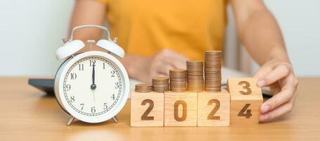 Happy New Year with vintage alarm clock and flipping 2023 change to 2024 block. Resolution, Goals, Plan, Action, Money Saving, Retirement fund, Pension, Investment and Financial concept photo