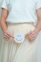 Woman hold Good and happy Face paper over abdomen. Ovarian and Cervical cancer, Endometriosis, Hysterectomy, Uterine, Reproductive, menstruation, Infertility, Pregnancy and Sexual Transmitted disease photo