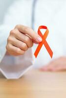 Doctor with Orange Ribbon for Leukemia, Kidney cancer day, world Multiple Sclerosis, CRPS, Self Injury Awareness month. Healthcare and word cancer day concept photo