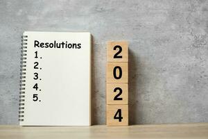 2024 Happy New Year with Resolution notebook and wooden number. countdown, Goals, Plan, Action and Mission Concept photo