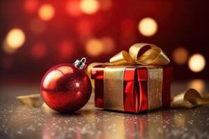 Photo of bokeh effect background, red gift box with gold ribbon and red and gold glitter christmas ornament.