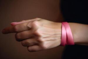 A close - up photography focusing on a woman's hands forming a heart shape with a pink ribbon against a soft pink background. Breast Cancer. photo