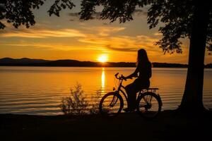 A low angle, her silhouette framed against the sunset, mountain bike by her side. Generative AI photo