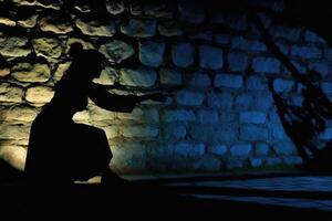 A dramatic image showcasing the silhouette of a witch cast by candlelight onto an old stone wall. photo