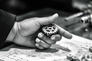 A mechanical hand reaching out to a human hand across a table strewn with gears and blueprints. Generative AI photo