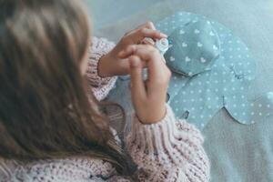 Close-up of a child's hands sewing a soft toy. The girl sews up a soft toy of an elephant. Handmade, hobby. photo