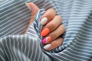 Beautiful female hands with manicure on a sea background. Stylish nail design. Summer manicure with orange and pink pattern on the nails. Copy space. photo