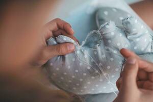 Close-up of a child's hands sewing a soft toy. The girl sews up a soft toy of an elephant. Handmade, hobby. photo