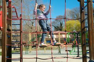 un niño sube en un cuerda patio de recreo al aire libre en un parque foto