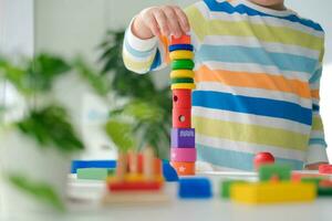 A little boy plays with wooden toys and builds a tower. Educational logic toys for children. Montessori games for child development. Children's wooden toy. photo