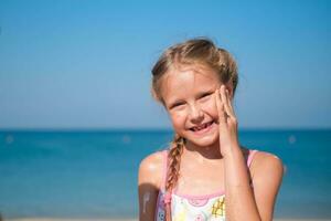 The girl smears her face with sun cream on the sea. photo