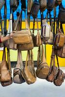 Close-up view of background of numerous black and brown leather bags hanging in rows. photo