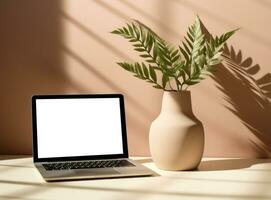 Table with vase and empty screen laptop on wallpaper photo