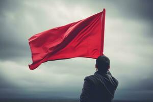 Hand holding red flag against blue sky photo